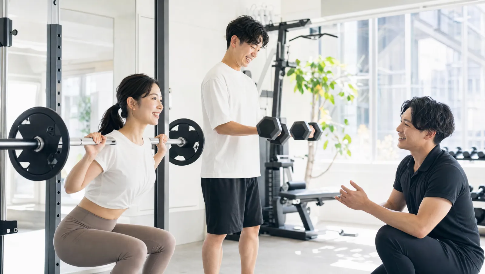 明るい完全個室でふたり並んでセミパーソナルトレーニングに取り組む新郎新婦とトレーナー