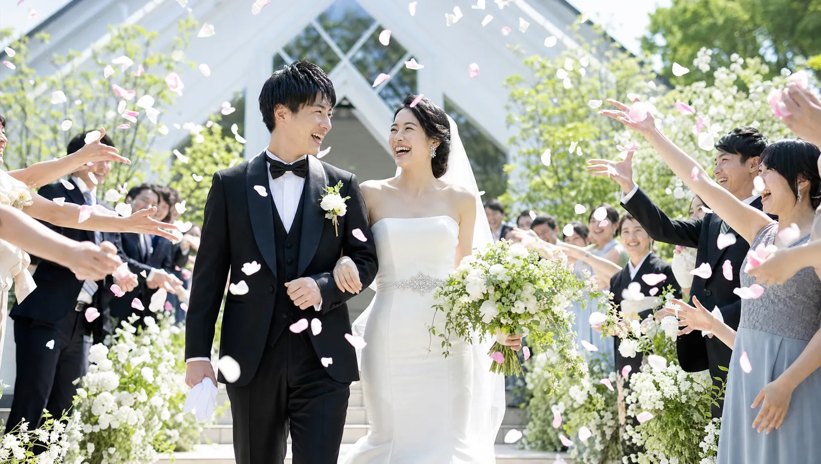 挙式を終え花びらの中を笑顔で歩く新郎新婦